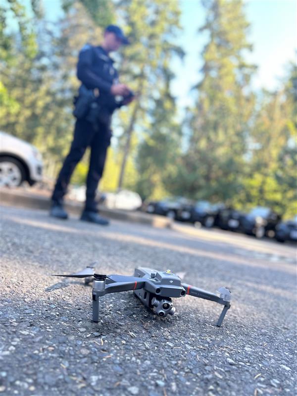 Police officer stands in the background with a drone remote. Police drone landed.